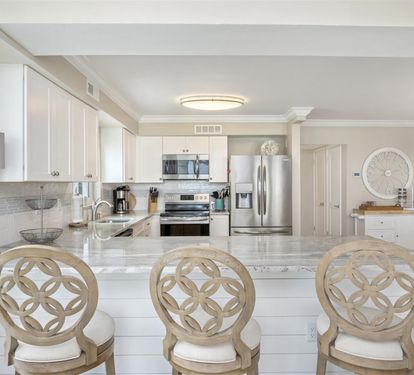 Your elegant kitchen awaits with gleaming marble countertops, stainless steel appliances, and stylish bar seating perfect for morning coffee or evening conversations.