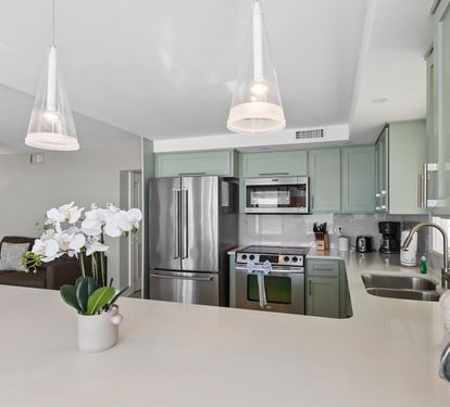 Step into your sleek kitchen featuring sage-green cabinets, granite countertops, and premium stainless appliances—perfect for preparing memorable meals.