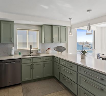 Cook with stunning ocean views from your modern kitchen featuring sage green cabinets and gleaming countertops.