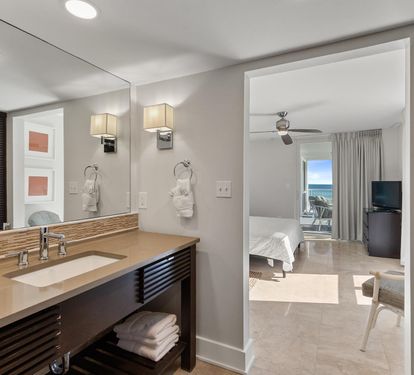 Sophisticated bathroom with modern vanity opens to your bright bedroom with stunning ocean views.