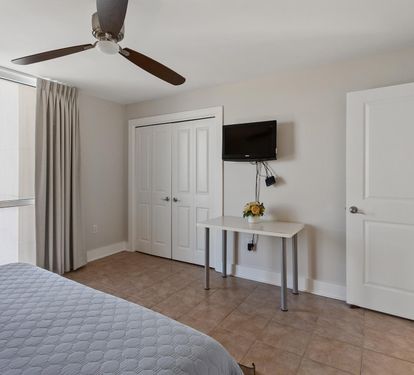 Your bright bedroom features modern comforts with a ceiling fan, wall-mounted TV, and dedicated workspace for both rest and productivity.