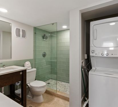Your modern bathroom features spa-inspired green tiles and glass shower, plus convenient stacked washer-dryer for ultimate comfort.