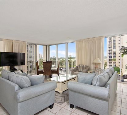 Unwind in your bright living space with plush seating and panoramic city views through floor-to-ceiling windows.