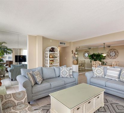 Unwind in your spacious living room with soft blue sofas, coastal décor, and gentle natural light streaming through.