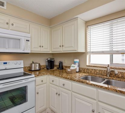 Your fully equipped kitchen features granite countertops, white appliances, and everything needed to prepare meals during your stay.