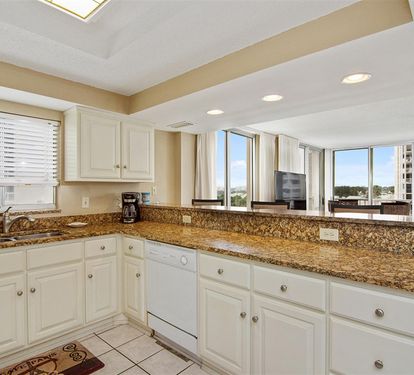 Whip up your favorite meals in this spacious kitchen featuring granite countertops, white cabinetry, and stunning city views from wraparound windows.