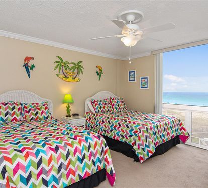 Wake up to stunning ocean views from your vibrant bedroom, where tropical decor and colorful chevron bedding create a cheerful coastal retreat.