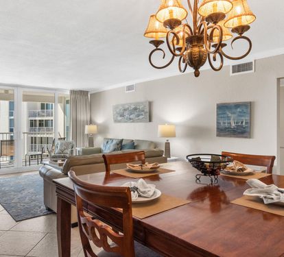Your elegant dining space flows seamlessly into the living area, where warm wood tones and coastal artwork create the perfect atmosphere for memorable meals.