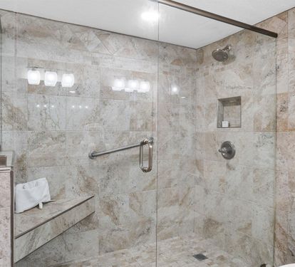 Step into your luxurious spa-like bathroom featuring elegant marble tiling and a spacious glass walk-in shower.