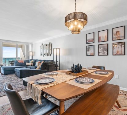 Settle into this bright open-concept space where modern comfort meets coastal charm. Your dining table awaits intimate meals while ocean views create the perfect backdrop.
