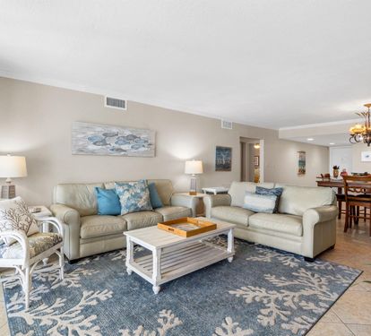 Sink into plush sofas in your spacious living room, where coastal blues and whites create a serene atmosphere for relaxing after beach adventures.