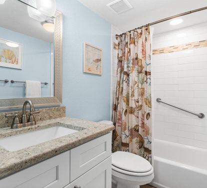 Refresh in your private bathroom featuring granite countertops, coastal artwork, and a relaxing tub-shower combo with charming seashell curtains.
