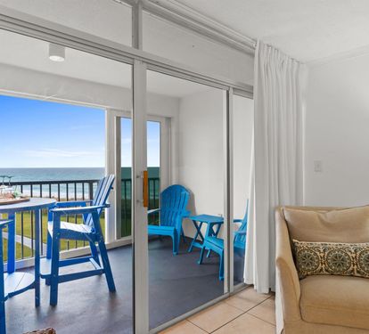 Relax in your bright living space while enjoying stunning ocean views from your private balcony with colorful beachside seating.