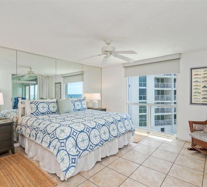 Wake up refreshed in your airy bedroom with coastal blue linens and a cozy wicker chair perfect for morning coffee.