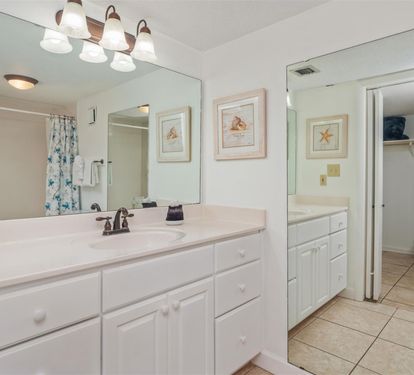 Refresh in your spacious bathroom featuring dual vanities, ample storage, and coastal-themed artwork that brings beach vibes to your morning routine.