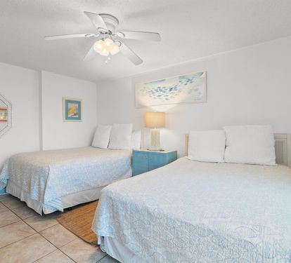 Rest easy in your peaceful bedroom with twin beds, gentle ceiling fan, and calming coastal decor for ultimate relaxation.