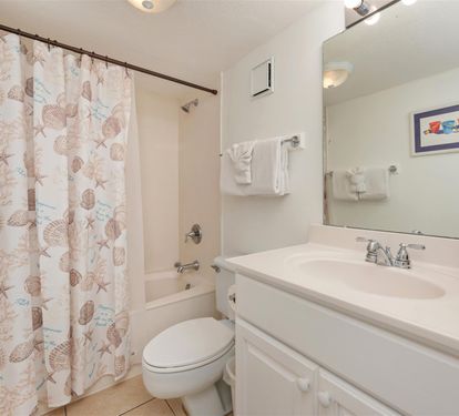 Your private bathroom features a relaxing tub-shower combo with coastal-themed curtain and fresh towels waiting.