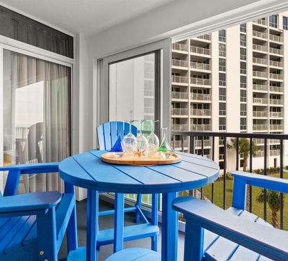 Sip your morning coffee on your private balcony while enjoying ocean glimpses and vibrant blue coastal furniture.