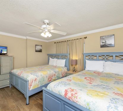 Your spacious bedroom features two comfortable beds with cheerful floral linens, perfect for family getaways or sharing with friends.