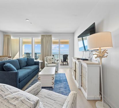 Your coastal living room features plush seating and oceanfront balcony access for perfect relaxation.