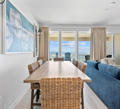 Gather around the natural wood dining table while gazing at stunning ocean views through floor-to-ceiling windows.