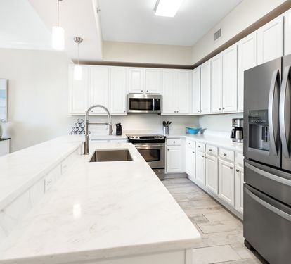 Your fully equipped kitchen features gleaming quartz countertops, stainless steel appliances, and bright white cabinetry—perfect for preparing everything from quick breakfasts to memorable vacation dinners together.
