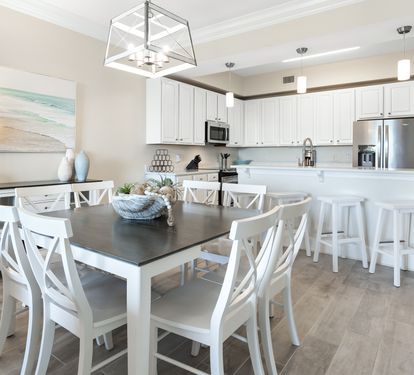 Gather around this bright, coastal-inspired dining space and fully equipped kitchen, where white cabinetry and modern appliances set the stage for your meals and memories together.