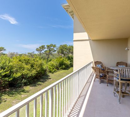 A spacious outdoor terrace overlooks lush coastal greenery under clear blue skies, offering the perfect spot to dine al fresco or simply unwind.