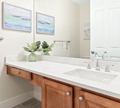 Refresh in your bright, stylish bathroom with coastal-inspired art, warm wood accents, and a pristine vanity designed for your comfort.