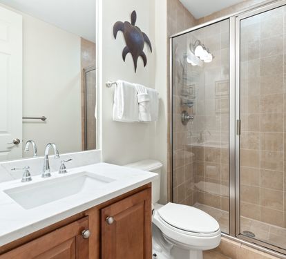 Your private bathroom features a spacious walk-in shower, fresh linens, and coastal charm with warm tile accents throughout.
