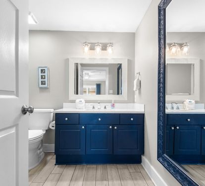 Step into your spa-like bathroom where a bold navy vanity meets soft gray walls and gleaming fixtures. Freshen up at the spacious counter with plenty of natural light flowing in.