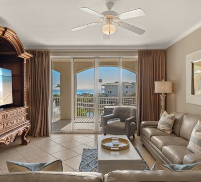 Unwind in the elegant living space with leather seating, entertainment center, and stunning balcony views of the coastline beyond.