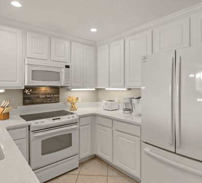 Fully equipped kitchen features white cabinets, granite countertops, and all essential appliances for preparing your favorite meals during your stay.