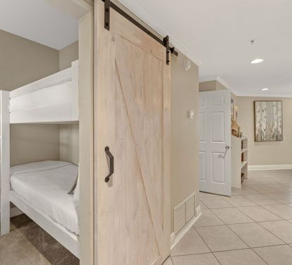 Kids will love this clever bunk bed setup with a rustic barn door for privacy and cozy carpeted floors.