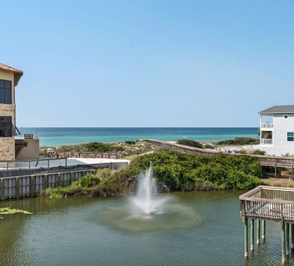 Coastal property featuring direct beach access via boardwalk, tropical landscaping, and stunning ocean views in a serene beachfront community.