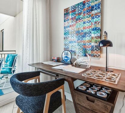 Your private workspace overlooks the balcony, where coastal-themed art and modern furnishings create an inspiring atmosphere for work or relaxation.