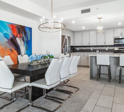 Gather around your elegant dining table with modern white chairs, while vibrant artwork energizes your open-concept kitchen space.