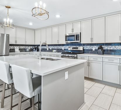 Your gourmet kitchen features sleek white cabinetry, granite countertops, and modern stainless appliances - perfect for preparing memorable meals during your stay.
