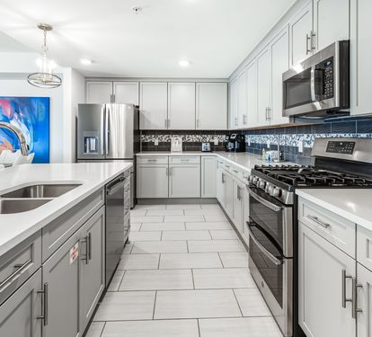 You'll love creating meals in this stunning modern kitchen with sleek white cabinetry, stainless appliances, and beautiful tile backsplash.