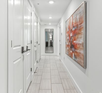 Step through your bright, gallery-style hallway where modern art meets pristine white walls, creating an elegant path to your private retreat.