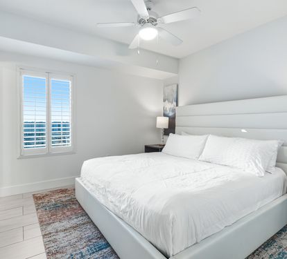 Drift off in your tranquil bedroom with crisp white linens, soothing coastal views through plantation shutters, and a gentle ceiling fan overhead.
