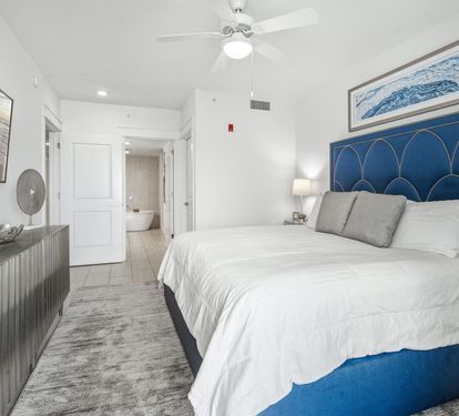 Drift off in your coastal-inspired bedroom with ocean artwork and crisp linens beneath a gentle ceiling fan.