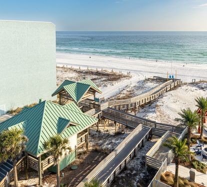 Beachfront property with direct access to pristine white sand beaches and emerald Gulf waters via elevated walkways.