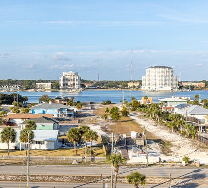 Coastal community featuring waterfront homes, high-rise buildings, and marina access across the bay.