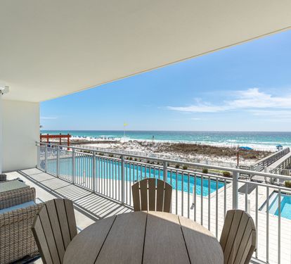 Relax on your private balcony with stunning ocean views, poolside dining table, and comfortable seating overlooking pristine beach.