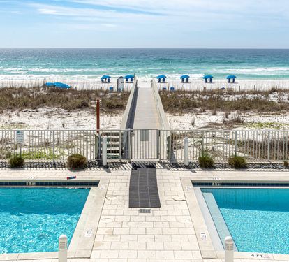 Pristine beachfront resort with swimming pool, boardwalk access to white sand beach and emerald waters.