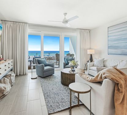 Unwind in your bright living room with stunning ocean views through floor-to-ceiling windows and cozy seating perfect for relaxation.