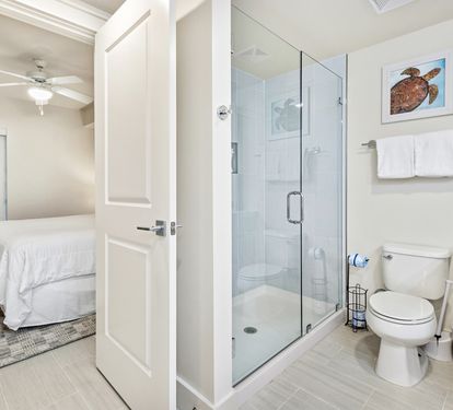 Your private bathroom features a glass walk-in shower, modern fixtures, and fresh towels, with your comfortable bedroom just steps away.