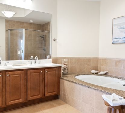Unwind in your spa-inspired bathroom with dual sinks, a walk-in shower, and a soaking tub framed by warm granite—a perfect retreat after exploring the coast.