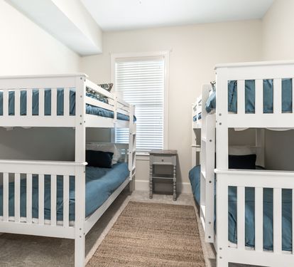Perfect for families or groups, this bright room features two white bunk beds with deep teal linens, offering cozy sleeping space for kids or friends traveling together.